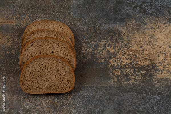 Fototapeta Sliced black rye bread on marble background