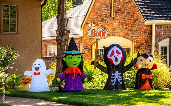 Fototapeta Halloween decorations - Goblins and spooks in the neighborhood - cute ghost witch skeleton with boo sign and vampire in front of house