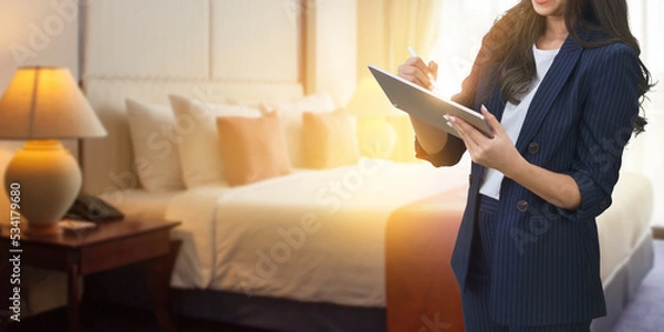 Fototapeta Businesswoman checking job reports with a tablet at hotel room blurred background