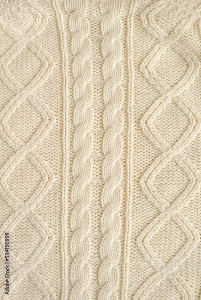 Fototapeta knitted milk sweater with a pattern of braids close-up. Knitted natural wool yarn texture. Texture