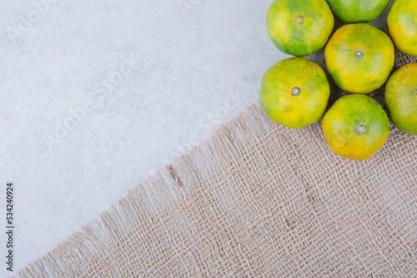 Fototapeta Several fresh sour whole tangerines on sackcloth