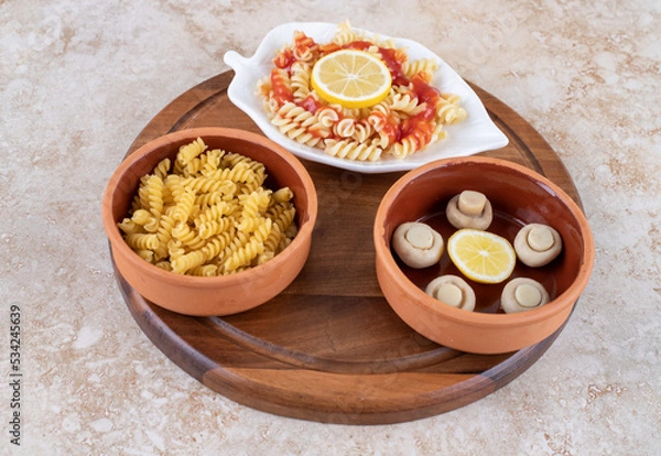 Fototapeta Two portions of pasta with a bowl of mushrooms on marble background