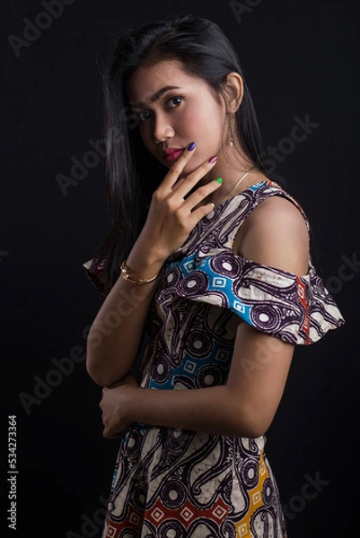 Obraz Beautiful young asian woman wearing batik isolated on black background. Batik Day.
