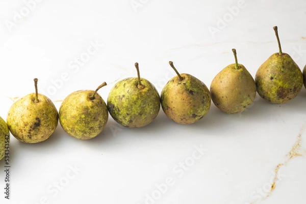 Fototapeta juicy green duchess pears harmoniously lie in the composition on a light white marble background