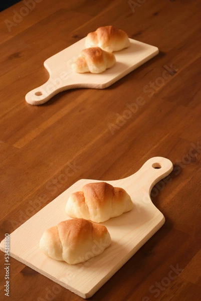 Fototapeta Two "rolls" on a cutting board x2 are placed on a wooden table