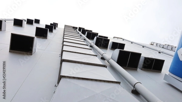 Fototapeta Ventilation pipe next to the building wall. Metal pipes with many vents of a department store for control and decontamination for safety on gray building background in bottom view. Selective focus