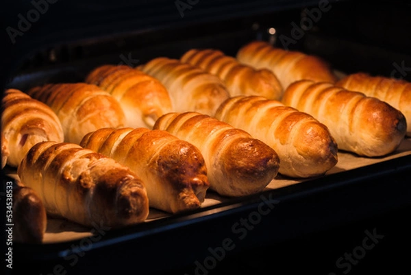 Fototapeta Sausages in the dough in the process of cooking