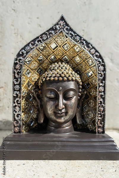 Obraz Buddha statue near house in front of wall.