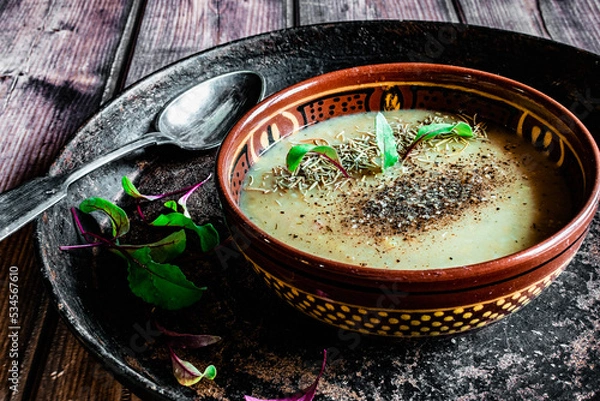 Fototapeta Pea soup puree with spices in a vintage dish and a plate with spices, rare cutlery, homemade food in the village