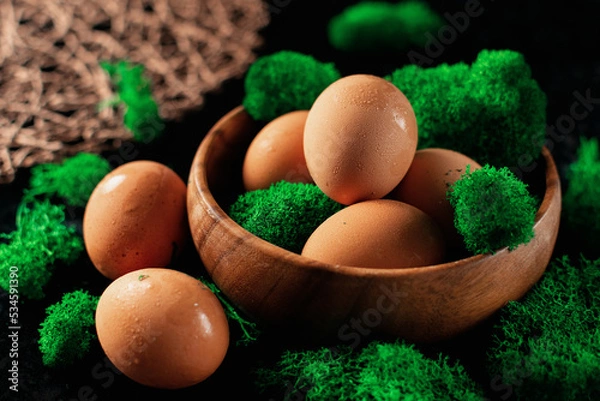 Fototapeta Chicken eggs in a wooden plate, there is a lot of natural green moss around, a homemade village product, fine water condensation on the eggs due to temperature changes