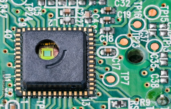 Fototapeta Green silicon die and gold wires inside round hole of integrated circuit. Close-up of optoelectronic sensor on PCB of optical laser computer mouse with surface mount assembly of electronic components.