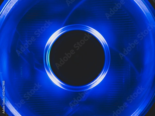 Fototapeta Computer cooling fan with blue light abstract background. cooler in action with led close up. power in motion concept