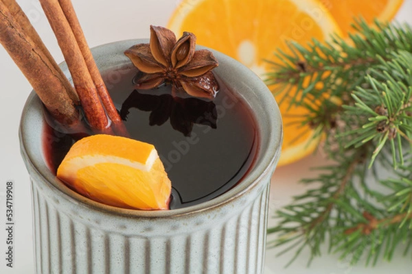 Fototapeta Christmas mulled wine. Punch, grog. The drink is decorated with an orange slice, anise and cinnamon.
Next to him are oranges and spruce branches. Close-up, top view. Composition on a light background.