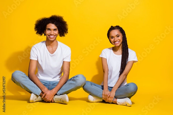 Fototapeta Full size portrait of two positive nice people sit floor have good mood rest isolated on yellow color background