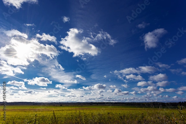 Fototapeta Landscape with direct sunshines, grass, clouds and blue sky