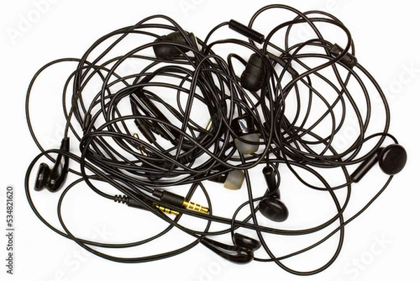 Fototapeta Old tangled headphones on a white background. Isolated. Black dusty dirty wired headphones with tangled wires. Audio Speakers, microphones, plugs and volume controls. Built-in vacuum music headset.