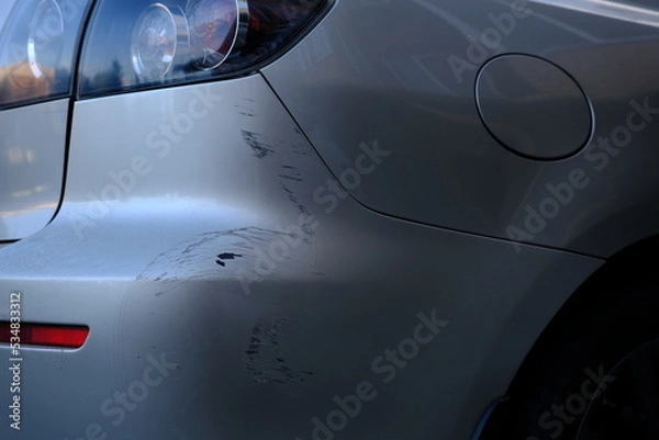 Fototapeta Scratched back bumper on the grey metallic car. Closeup image of damaged back bumper on the car. Photo for the insurance company of a scratched car.