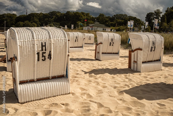 Fototapeta Wicker roofed beach chairs at the sand beach. Strandkorb at north seashore. 