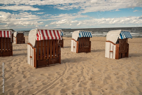 Fototapeta Wicker roofed beach chairs at the sand beach. Strandkorb at north seashore. 