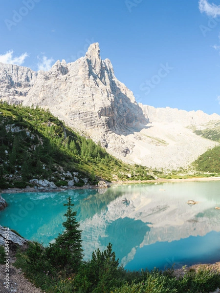 Fototapeta Stunning view of the Lake Sorapis (Lago di Sorapis) with its turquoise waters surrounded by a forest and beautiful rocky mountains, Dolomites, Italy.