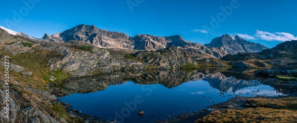 Fototapeta In the Alps, beautiful panoramic view of the lake of bellecombe and the surrounding mountains reflected in the waters of the lake