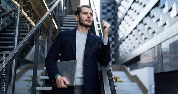 Fototapeta a male cybersecurity specialist in a business suit on the background of the stairs of an office building