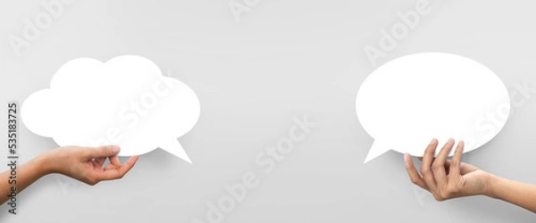 Fototapeta Hand holding of empty white speech bubble against and white cloud shape at grey background.