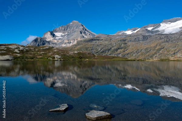 Fototapeta The majestic summit of the Dent Parrachee reflected in the waters of Lake Blanc in the French Alps in the Vanoise National Park