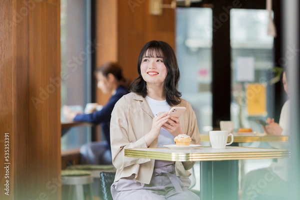 Fototapeta カフェでスマホを見る若い女性