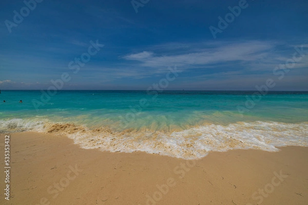 Fototapeta Beautiful view of rolling turquoise wave on sandy beach in Atlantic ocean on island of Aruba.