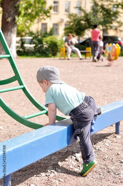 Obraz Little boy tries to get on a children's ladder