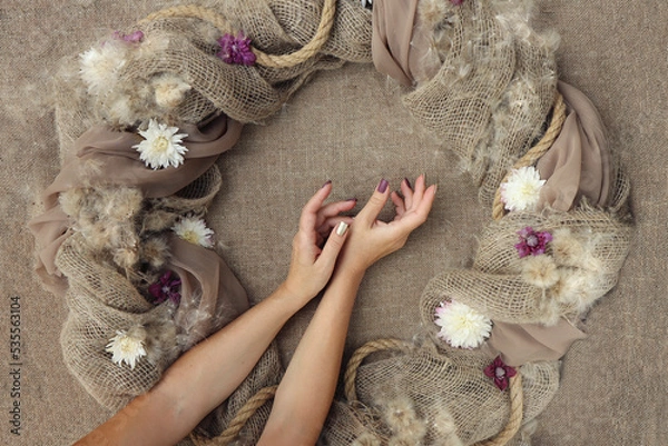 Fototapeta Decorative decoration with flowers on burlap with female hands.