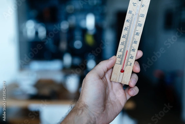 Fototapeta Energy crisis in Europe. A man's hand holds a thermometer with a temperature close to zero in his apartment.