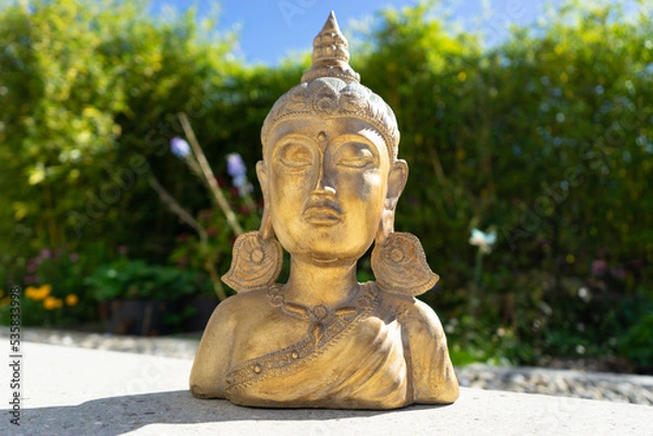 Obraz Buddha statue near house in front of garden.