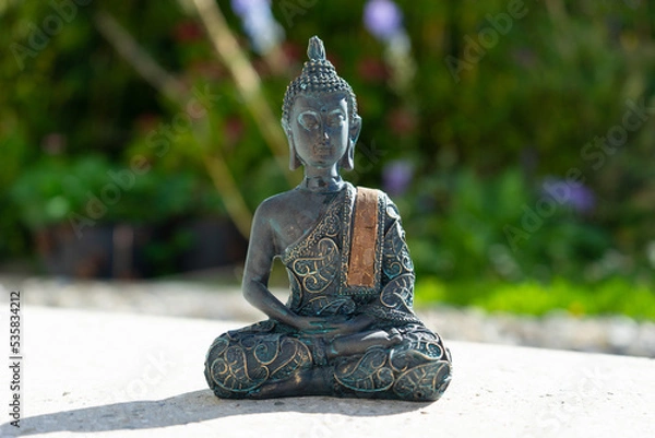 Obraz Buddha statue near house in front of garden.