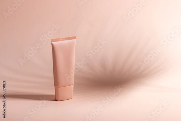 Fototapeta Cosmetic cream or mask in a white tube with hard shadows from the leaves on a white background. Natural organic care for face and body skin. View from above.