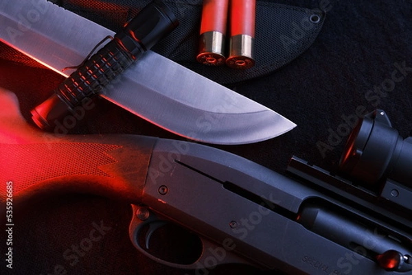 Fototapeta Weapon on black cloth: flashlight, knife, rifle, shells,top view. Top view of knife, rifle, shells.