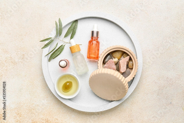 Fototapeta Board with bottles of essential olive oil on light background