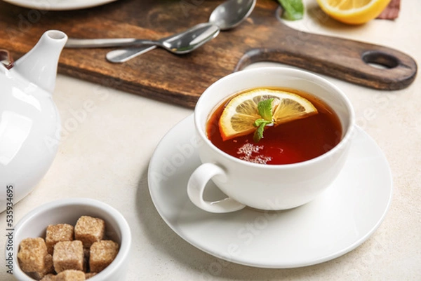 Fototapeta Cup of black tea with lemon and mint on white table, closeup