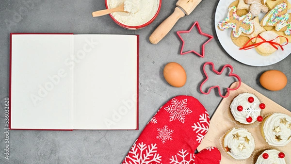 Fototapeta Open copy space book for recipe and Chrsitmas cookies and igredinets for baking on the table. Flat lay