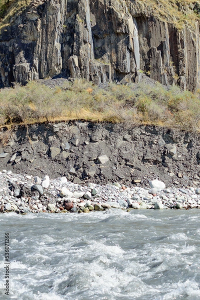 Fototapeta White water of the  mountain stream in summer time. Torrent waves, white and brown stones, green grass rocky slopes on the bank