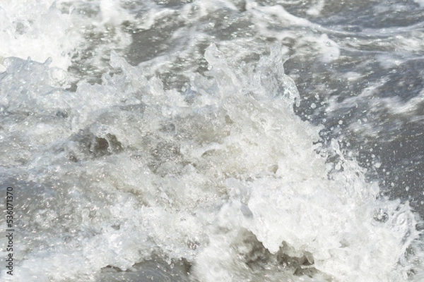 Fototapeta Close-up white water of the mountain stream in a summer day. White and grey foam of waves and drops of water