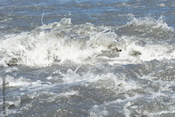 Fototapeta Close-up white water of the mountain stream in a summer day. White and grey foam of waves and drops of water