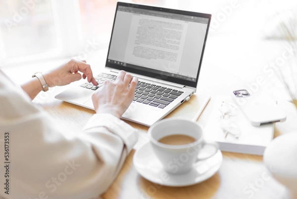 Obraz Close-up of keyboard keys on a laptop. Women's hands are typing text in a document. Buisness process.