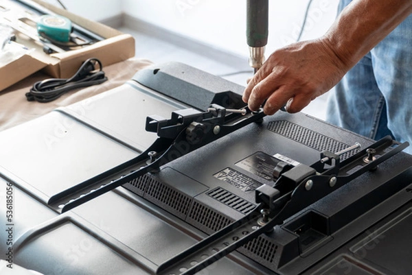 Fototapeta man installing the wall base for the television, it is a smart tv, adjusting with screwdriver
