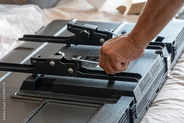 Obraz Handyman using screwdriver to fix tv, repair and installation services
