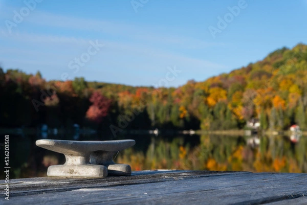Fototapeta A cleat on dock waits for a boat to tie up on this small lake.
