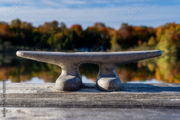 Fototapeta A cleat on dock waits for a boat to tie up on this small lake.