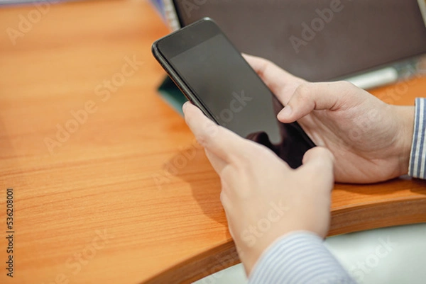 Fototapeta man hand holding smartphone on desk