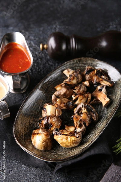 Fototapeta Grilled vegetables. Fried mushrooms with herbs on a plate, red and white sauces, ketchup, spices. Rosemary on a dark table. Turkish cuisine, dish. Vegetable garnish. Background image, copy space